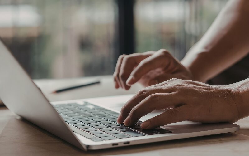 Person typing on laptop, representing online security and scam awareness