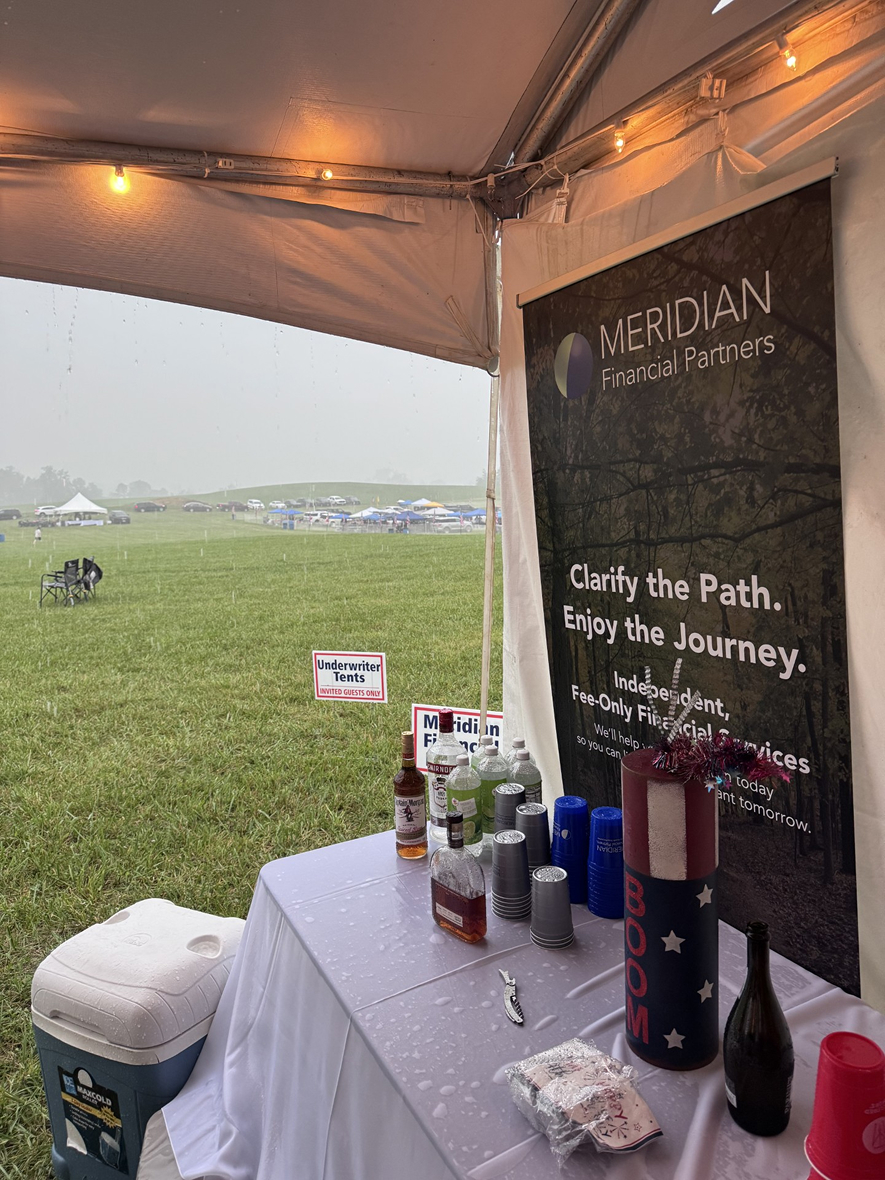 View from inside a tent showing a table and a Meridian Financial Partners banner event